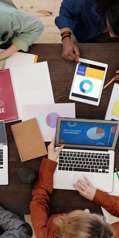 A diverse team collaborating on digital marketing strategies at a desk, using laptops and tablets.